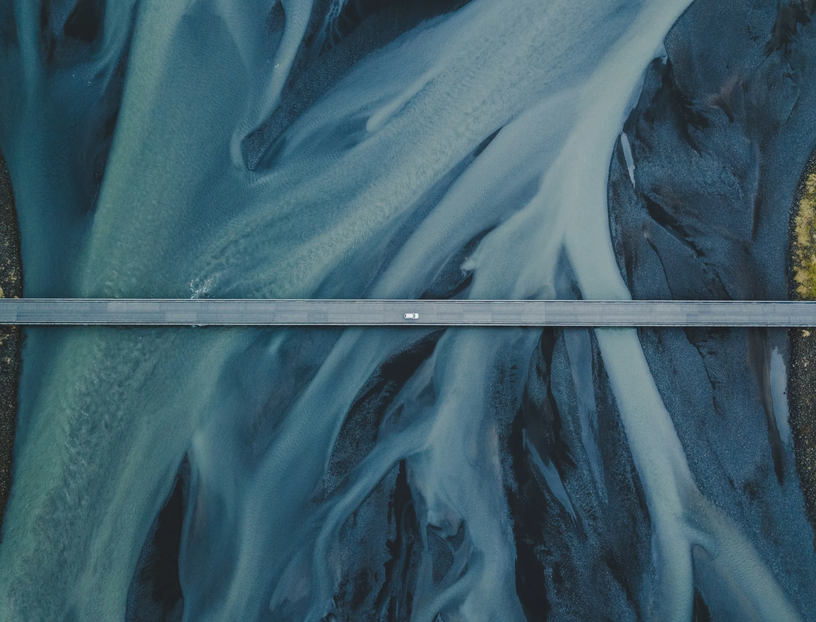 Aerial view of a blue glacial river winding through sediment